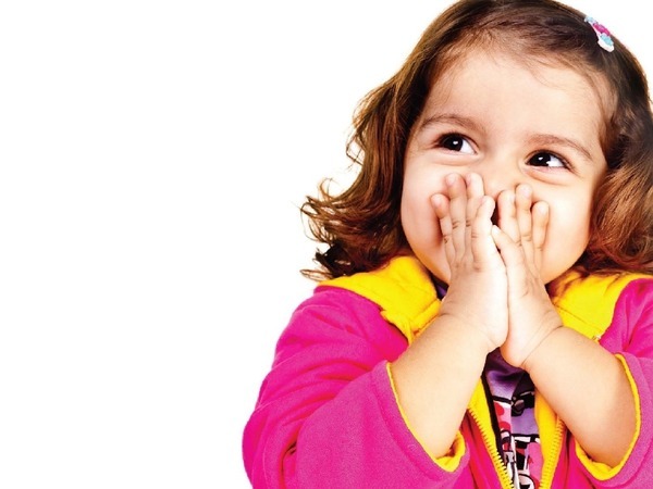 One infant holding her hands to over her mouth, hiding a big smile 