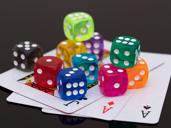 Some colourful dice in an informal arrangement on top of three playing cards
